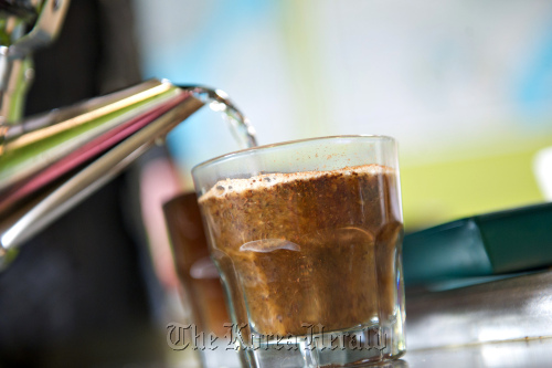 Hot water is poured into a glass of ground Ethiopian coffee.   Bloomberg