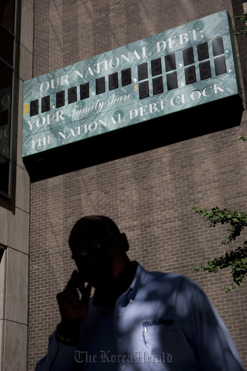 A pedestrian walks past “The National Debt Clock,” displayed on the side of a building near an Internal Revenue Service office in New York.  Bloomberg