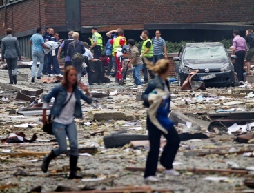 Two women are seen leaving as rescue workers arrive to help the injured following an explosion in Oslo, Norway Friday July 22, 2011. (AP)
