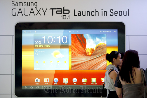 Visitors stand next to a billboard showing the Galaxy Tab 10.1 at Samsung Electronics Co. headquarters in Seoul. Bloomberg