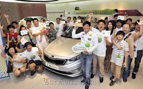 Consumers pose with the Kia Motors K5 hybrid during the automaker’s event to select “eco-friendly drivers.”  Kia Motors Corp.