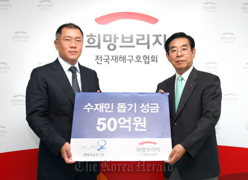 Chung Eui-sun (left), vice chairman of Hyundai Motor Group, poses with Han Joong-gwang, chairman of Korea Disaster Relief Association, after donating 5 billion won as a relief fund to help those suffering from rain damages. Hyundai Motor
