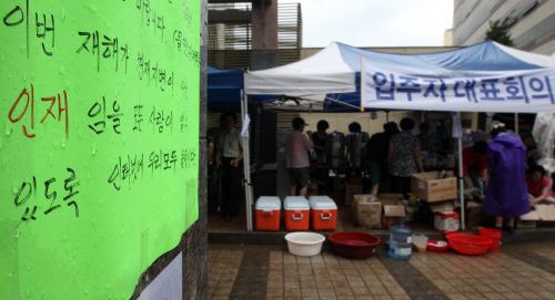 <YONHAP PHOTO-1041> '천재지변 아닌 인재' (서울=연합뉴스) 배정현 기자 = 우면산 산사태로 큰 피해를 입은 서울 방배동 한 아파트 단지에 31일 오전 '이번 재해는 천재지변이 아닌 인재'라고 쓰인 안내문이 붙어있다. 2011.7.31 doobigi@yna.co.kr/2011-07-31 14:16:00/ <저작권자 ⓒ 1980-2011 ㈜연합뉴스. 무단 전재 재배포 금지.>
A sign reading “the landslide was a man-made disaster” hangs on the wall of an apartment building in Bangbae-dong, southern Seoul, on Sunday. Yonhap News