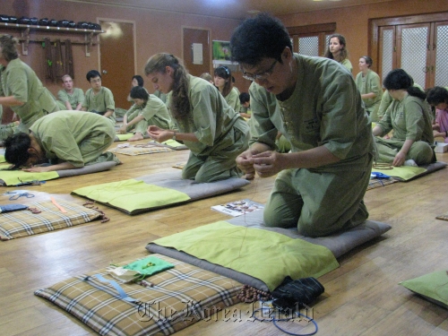 Lee Ho-lim (foreground) and other Templestay participants make rosaries on a recent morning at the Myogak Temple in Jongno, Seoul.  Rob York/The Korea Herald\r\nLee Ho-lim (foreground) and other Templestay participants make rosaries on a recent morning at the Myogak Temple in Jongno, Seoul.  Rob York/The Korea Herald