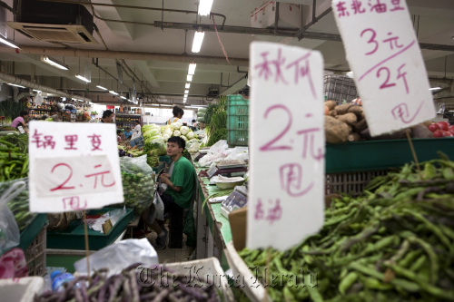Vegetables and prices are displayed as a vendor waits for customers at a market in Beijing.  Bloomberg