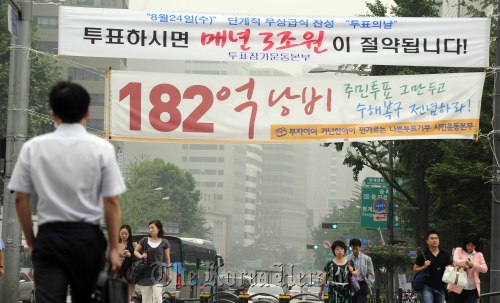 서울시 무상급식 주민투표 실시와 중단 여부를 따지는 법원의 결정이 오늘 16일 내려질 예정인 가운데 서울시 중구 종각근처로 출근하는 시민들이 무상급식 찬반으로 나위는 현수막을 보면서 발걸음을 재촉하고 있다. 박해묵 기자/mook@heraldm.com\r\nTwo banners showing opposite views on the upcoming plebiscite on free school meals hang over a street in Jongno, Seoul, on Tuesday. One urges citizens to participate in the vote, while the other calls it a waste of tax payers’ money.  Park Hae-mook/The Korea Herald