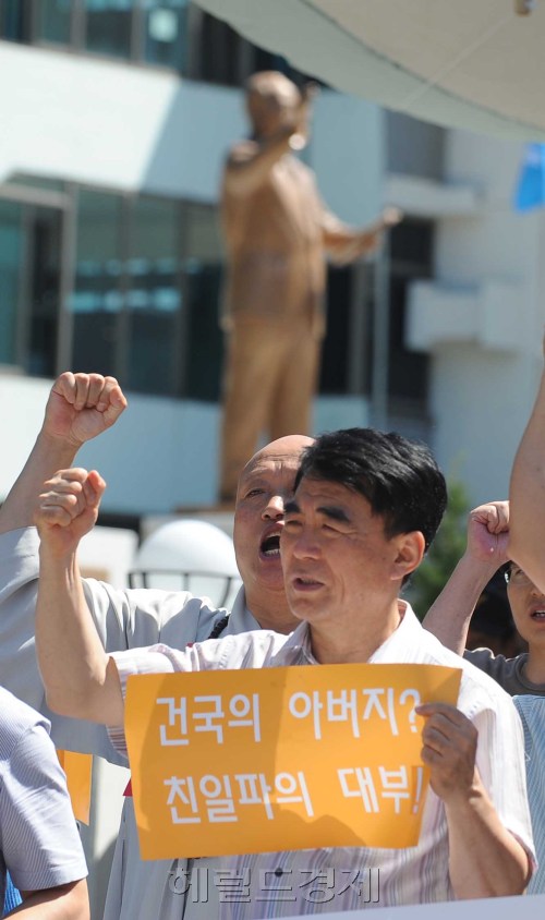 25일 오전 서울 남산 자유총연맹광장앞 인도에서 열린 이승만 전대통령 동상 제막시에 반대하는 시민들이 제막식 규탄 집회를 갖고 있다. 뒤쪽에 이승만 전대통령 동상이 웅장하게 서 있다.<br />이상섭 기자 babtong@heraldm.com 2011.08.25\r\n25일 오전 서울 남산 자유총연맹광장앞 인도에서 열린 이승만 전대통령 동상 제막시에 반대하는 시민들이 제막식 규탄 집회를 갖고 있다. 뒤쪽에 이승만 전대통령 동상이 웅장하게 서 있다.\n이상섭 기자 babtong@heraldm.com 2011.08.25
