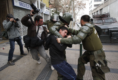 <YONHAP PHOTO-0369> Riot police officers try to detain a demonstrator and a photojournalist during a national strike in Santiago, Chile, Wednesday, Aug. 24, 2011. Some people are stoning buses and burning barricades as Santiago's streets fill with tear gas. Protesters planned marches downtown, but the government has warned them to stay out, threatening to invoke Chile's severe state security law against people who "incite the subversion of public order." (AP Photo/Luis Hidalgo)/2011-08-25 05:37:41/ <저작권자 ⓒ 1980-2011 ㈜연합뉴스. 무단 전재 재배포 금지.>\r\nPolice officers try to detain a demonstrator and a photojournalist during a national strike in Chile on Wednesday. AP-Yonhap News
