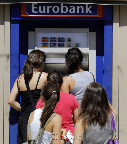 Customers queue to use an EFG Eurobank Ergasias SA automated teller machine in Athens.  Bloomberg