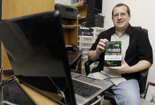 <YONHAP PHOTO-0375> ADVANCE FOR USE SUNDAY, AUG. 28, 2011 AND THEREAFTER - In this June 3, 2011 photo, Ryan Van Cleave holds a copy of his book "Unplugged" at his home in Sarasota, Fla. Gaming and thinking about video games was all-consuming for Van Cleave. Yet living inside the game World of Warcraft, which became his obsession, seemed preferable to the drudgery of everyday life. Especially when the life involved fighting with his wife about how much time he spent on the computer. While the game made him feel "godlike," life's small hitches could be "profoundly disempowering." Despite thoughts like this, recorded in his new book, despite dissociative episodes in supermarkets when he felt as if he was inside a game, he did not think he had a problem IRL _ gamerspeak for In Real Life. But he did, and a reckoning was coming. (AP Photo/Chris O'Meara)/2011-08-25 05:38:24/ <저작권자 ⓒ 1980-2011 ㈜연합뉴스. 무단 전재 재배포 금지.>\r\nRyan Van Cleave holds a copy of his book “Unplugged” at his home in Sarasota, Florida, on June 3.   AP-Yonhap News
