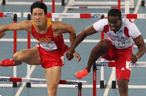 Dayron Robles (right) makes contact with Liu Xiang in the men's 110-meter hurdle final at the IAAF World Athletics Championships in Daegu on Monday. (Yonhap News)