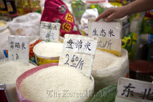 A vendor adjusts price displays in sacks of rice at a market in Beijing.  Bloomberg