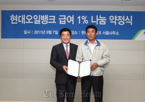 Hyundai Oilbank Co. chief executive Kwon Oh-gap (left) and the company’s labor union head Kim Tae-kyeong pose after agreeing Wednesday in Seoul to donate 1 percent of their pay to charity.\r\n Hyundai Oilbank Co.