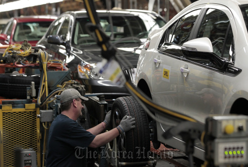 A worker puts a tire on a General Motors Co. 2012 Opel Ampera at Detroit-Hamtramck Assembly Plant in Michigan.  Bloomberg