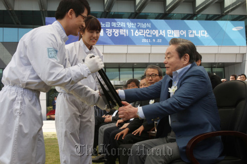 Samsung Electronics chairman Lee Kun-hee (right) receives the first semiconductor wafer produced in a new production line at a ceremony to mark the operation of Samsung’s 16th production line in Hwaseong, Gyeonggi Province, on Thursday.     Samsung Electronics