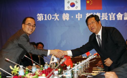 Korean Finance Minister Bahk Jae-wan (left) shakes hands with his Chinese counterpart Zhang Ping at the opening of the economic ministers’ meeting in Seoul on Wednesday.        Yonhap News