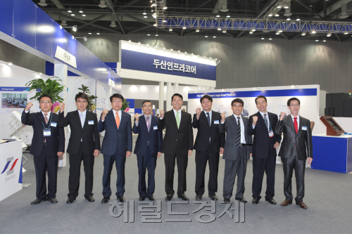 두산인프라코어가 28일 경기도 고양시 킨텍스 제2전시장에서 개최된 ‘2011 한국기계전(KOMAF)’에서 6개 협력 업체와 통합 부스를 설치해 제품 및 부품을 전시한 가운데 두산과 협력사 임직원들이 파이팅을 외치고 있다.