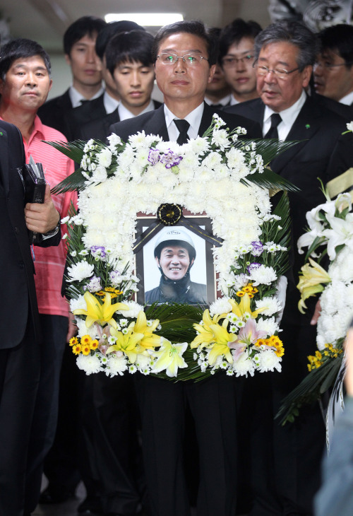 <YONHAP PHOTO-1335> 철가방 천사 김우수씨 빗속 눈물의 발인 (서울=연합뉴스) 김현태 기자 = '천사 배달원' 故 김우수씨의 발인날인 29일 오후, 빈소인 서울 영등포구 대림동 서울복지한방병원 장례식장에서 그와 마지막을 함께 하려는 시민과 각계 인사들이 함께한 가운데 김우수씨의 영정이 빈소를 떠나고 있다. 2011.9.29 mtkht@yna.co.kr/2011-09-29 14:38:51/ <저작권자 ⓒ 1980-2011 ㈜연합뉴스. 무단 전재 재배포 금지.>\r\nCitizens involved in Kim Woo-su’s charity work carry his coffin at the funeral ceremony on Thursday afternoon.   Yonhap News