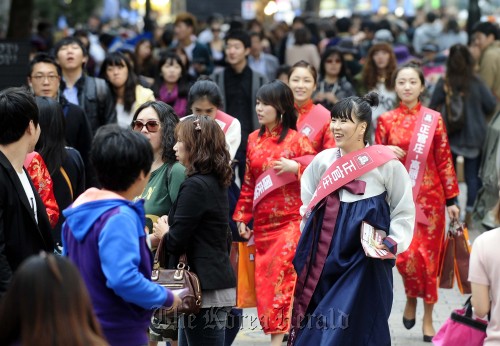 중국 국경절 연휴로 인해 중국관광객들이 한국을 많이 찾은 가운데 2일 오후 명동에는 중국 관광객들로 북적이고 있다. 박해묵 기자/mook@heraldm.com\r\nA sales team from the Korea Ginseng Corp. clad in Korean and Chinese traditional clothes promotes homegrown ginseng in Myeong-dong, downtown Seoul on Sunday as many Chinese tourists visit the area.  Park Hae-mook/The Korea Herald
