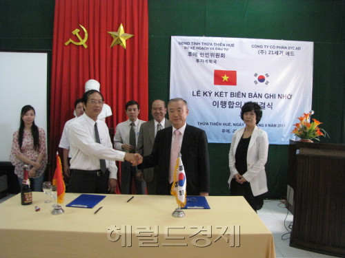21세기애드 이선국(앞줄 오른쪽) 회장과 베트남 후에성 성주가 지난 7월 성 전역에 대한 도로표지판 설치 사업 이행협약을 체결한 뒤 악수를 나누고 있다.