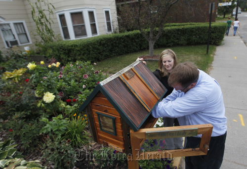 In front garden of the Lake Elmo Inn, with the help of the owner’s daughter, Laura Schiltz (left), Todd Bol installs a free library, Sept. 26. Minneapolis Star Tribune/MCT