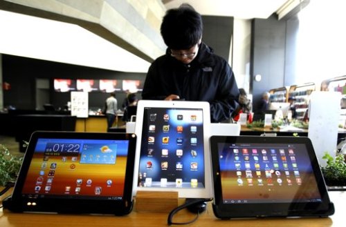 A student uses a mobile phone near the Samsung Electronics' new tablet Galaxy Tab 10.1 with Apple's white iPad on display, center, at the showroom in Seoul, (AP)