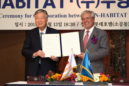 Booyoung Group Chairman Lee Joong-keun (left) and the U.N.-Habitat’s executive director Joan Clos pose after signing an agreement to fund the agency’s human settlements program at a ceremony in Seoul on Thursday.       Booyoung Group