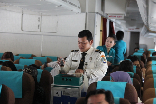 An immigration officer checks passports and visa application forms of passengers on board a Garuda light from Incheon to Jakarta. (Garuda Indonesia)