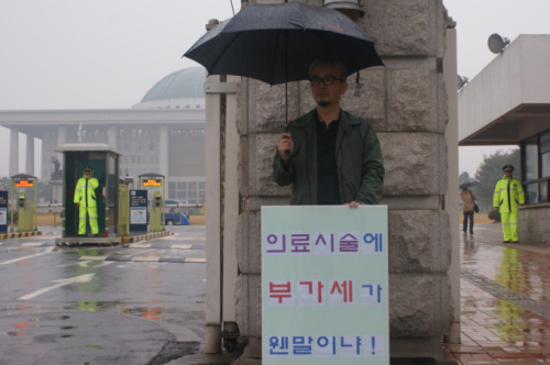 대한성형외과 의사회는 지난 9월에 이어 국회 앞에서 ‘성형수술 부가세’ 과세 반대 1인 릴레이 2차 시위를 지난 14일(금)에 추가로 갖었다.\r\n 성형외과 의사회에 따르면 지난 7월에 시행된 성형수술 5개 분야에 대한 부가세는 형평성에 어긋난다고 입장을 밝히며, 그러한 의견을 국회에 전하기 위해서 1인 릴레이 침묵시위를 2차적으로 진행했다고 전했다.\r\n 두 번째로 갖은 1인 릴레이 시위에는 황세휘 기획 상임이사와 최정호 무임소 상임이사, 홍정근 홍보 상임이사, 윤원준·황규석 법제 상임이사등 8명이 참여했다.  1인 릴레이 시위에 참여한 의사회 관계자는 "지난 7월1일부터 시행된 성형수술 부가세 항목은 미용성형 분야로 정하고 있는 쌍꺼풀수술, 코성형, 지방흡입술, 주름살제거술, 가슴확대와 축소술 등 5개 항목"인데 현실적으로는 치료성형(재건성형)과 미용성형을 나누기가 어렵다고 전했다.