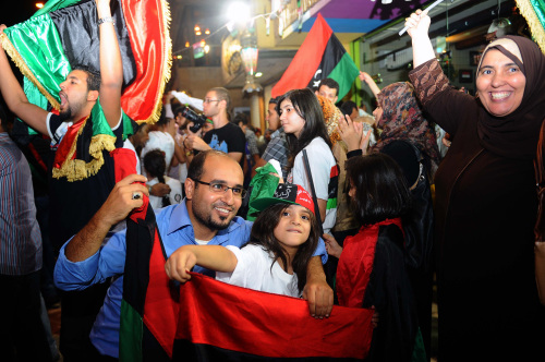 People wave pre-Gadhafi flags as they gather to celebrate the death of deposed Libyan dictator Moammar Gadhafi in Cairo, Egypt, Thursday. Moammar Gadhafi, Libya's dictator for 42 years until he was ousted in an uprising-turned-civil war, was killed Thursday as revolutionary fighters overwhelmed his hometown of Sirte and captured the last major bastion of resistance two months after his regime fell. (AP-Yonhap News)