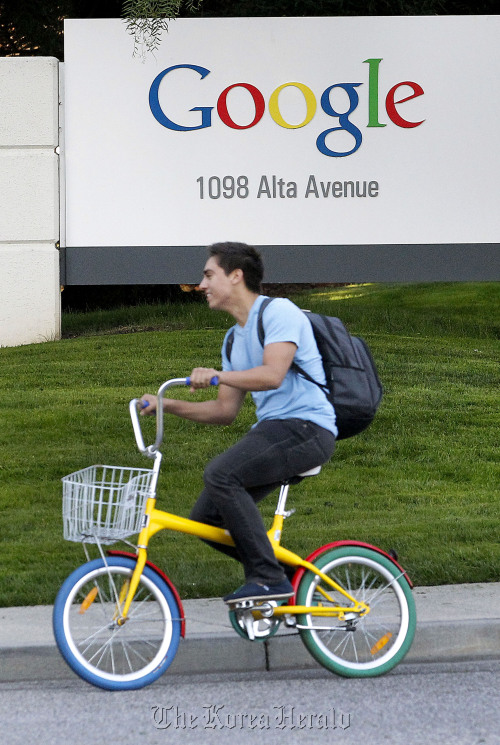 A Google Inc. employee rides a “G-bike” past signage displayed company headquarters in Mountain View, California.   Bloomberg