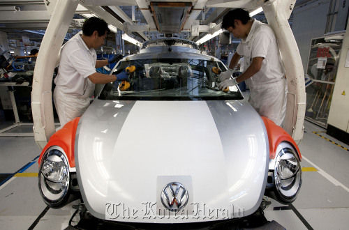 Employees place a windshield on the new generation Volkswagen AG Beetle at the company’s assembly plant in Puebla, Mexico.  Bloomberg