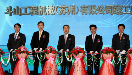 Doosan Group chairman Park Yong-hyun (center), Doosan Infracore Co. president and chief executive Kim Yong-sung (far left), the Suzhou Industrial Park Administrative Committee’s director Yang Zhiping (far right) and other officials cut the tape at a ceremony to mark the completion of the Korean firm’s plant in Suzhou, China to manufacture excavators on Wednesday.   Doosan Infracore Co.