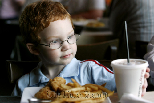 A child eats chicken strips and French fries.   MCT