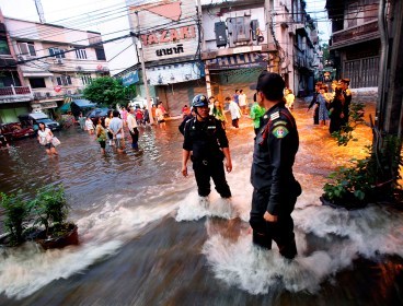 Metropolitan Police officers stand on a flooded road in Bangkok, Thailand, on Wednesday, Oct. 26, 2011. (Bloomberg)