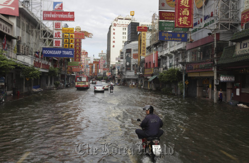 Local residents wade through floodwaters in Bangkok on Sunday. AP