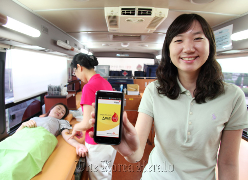 A model displays the app “Smart Blood Donation” on a mobile bus for giving blood.