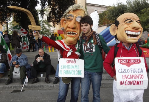 Demonstrators wear masks mocking Italian Premier Silvio Berlusconi (right) and Reform Minister Umberto Bossi carrying placards reading: "Silvio, change my diaper", left, and "I'm looking for confidence, payment in cash" during a demonstration staged by the Italian Democratic party in Rome, Saturday. (AP-Yonhap News)