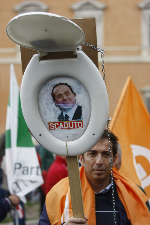 A demonstrator holds a toilet seat with a picture of the Italian Premier Sivlio Berlusconi and writing which reads: " Expired" during a demonstration staged by the Italian Democratic party in Rome, Saturday. (AP-Yonhap News)