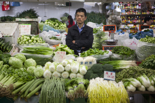 A vendor stands amongst produce at a market stall in Beijing.  Bloomberg
A vendor stands amongst produce at a market stall in Beijing.  Bloomberg
A vendor stands amongst produce at a market stall in Beijing.  Bloomberg