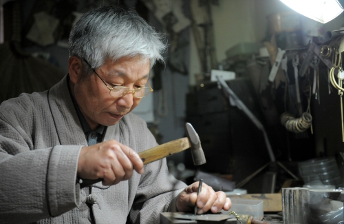 Metalwork artisan Park Moon-yeol hammers traditional patterns onto metal at his studio in Byeokje, Gyeonggi Province. (Ahn Hoon/The Korea Herald)