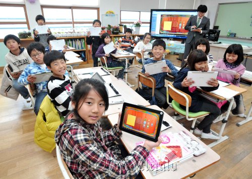 Students at Nohwa Elementary School on Wando, a remote island in South Jeolla Province, play with mobile devices provided by Samsung Electronics in a “smart classroom” on Thursday.  Samsung Electronics