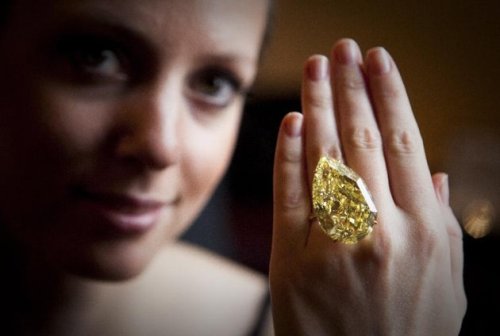 A model displays a 110.03 carats Sun-Drop Diamond described as fancy vivid yellow, the highest color grading, by gemstone experts, at a Sotheby's preview show in Geneva, Switzerland. (AP)
