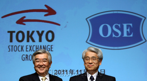 Atsushi Saito, president and chief executive officer of Tokyo Stock Exchange Group Inc. (left), poses with Michio Yoneda, president of Osaka Securities Exchange Co., during a photo session at a news conference in Tokyo on Tuesday.  Bloomberg