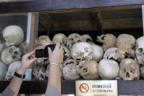 A tourist takes pictures of human skulls of Cambodian Khmer Rouge victims at Choeung Ek stupa, better known "Killing field" on the outskirts of Phnom Penh, Cambodia, Sunday. (AP-Yonhap News)