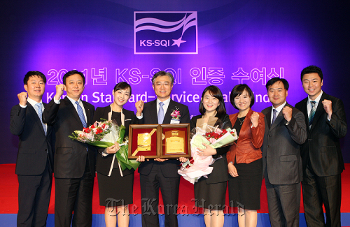 Shinhan Bank deputy CEO Kim Young-pyo (fourth from left) poses with employees during an event celebrating the commercial bank’s best service award from the Korean Standard-Service Quality Index for 2011 at a hotel in Seoul, Nov. 17.     Shinhan Bank