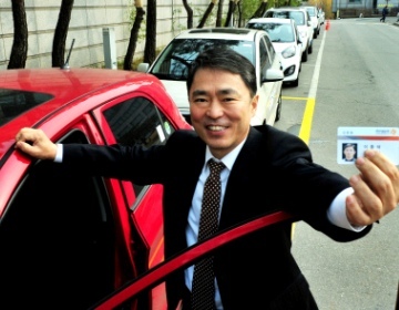 Rhee Jong-tae, dean at Dongguk University, holds up the card that gains him access to one of his carsharing vehicles. (Park Hyun-koo/The Korea Herald)