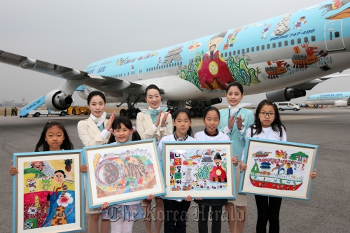 Winners of a Korean Air drawing contest pose with flight attendants in front of the aircraft wrapped with one of their paintings at the Gimpo Airport on Saturday.
Korean Air