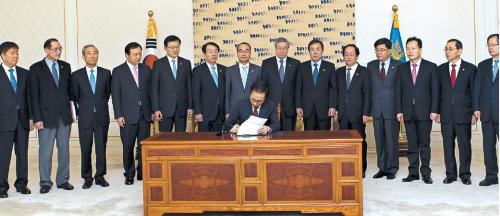 President Lee Myung-bak signs 14 related bills needed to implement the Korea-U.S. Free Trade Agreement at Cheong Wa Dae on Tuesday as chiefs of related ministries including Trade Minister Kim Jong-hoon (third from left) watch. (Yonhap News)