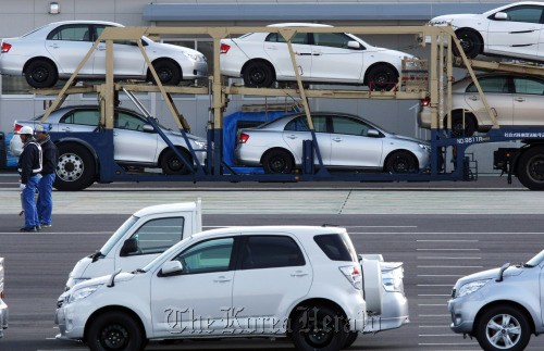 Employees work near Toyota Motor Corp. vehicles awaiting shipment at Central Motor Co.’s Miyagi plant in Ohira village, Miyagi prefecture, Japan.  Bloomberg